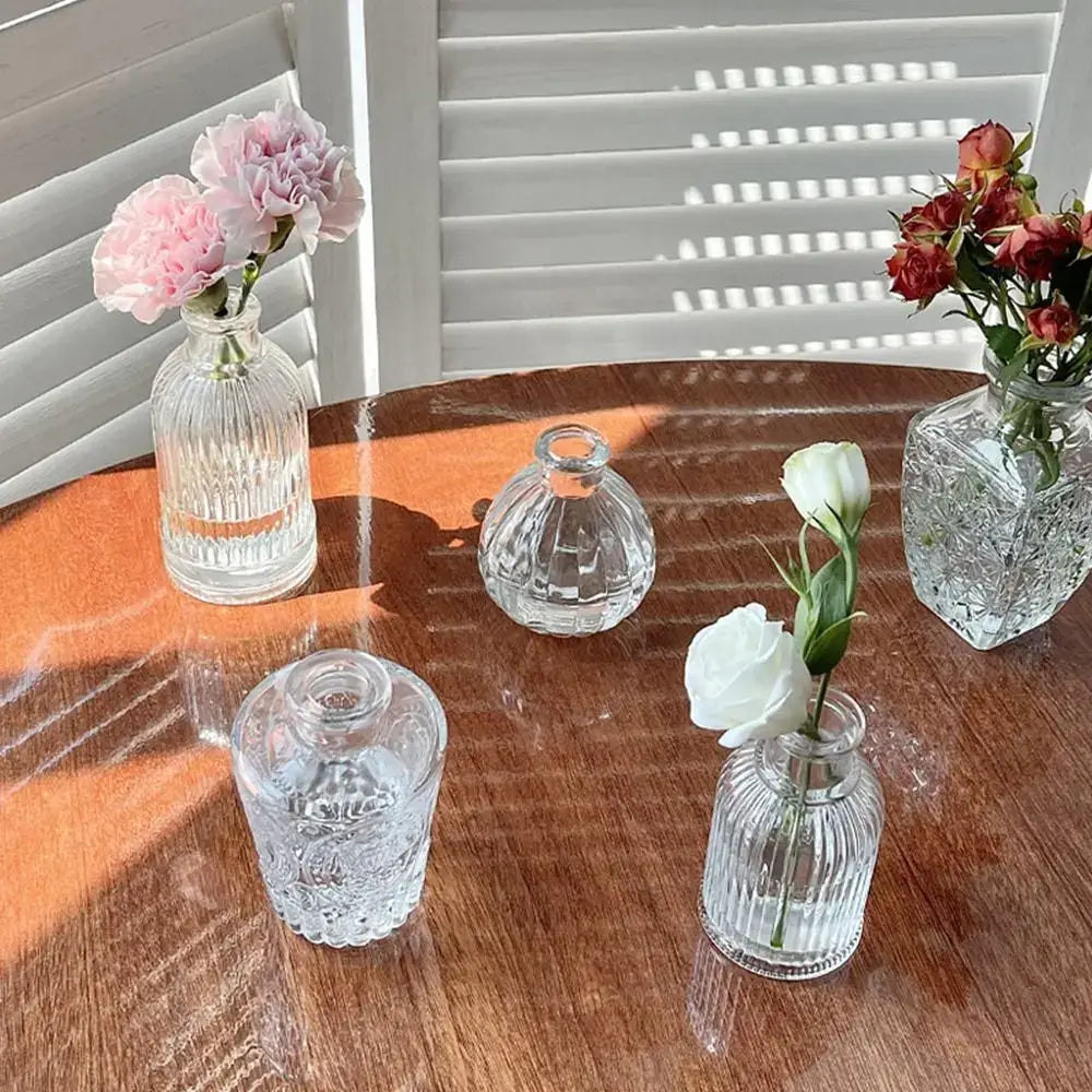 Clear glass vintage relief vases with intricate cut patterns holding single flowers for hydroponic plants