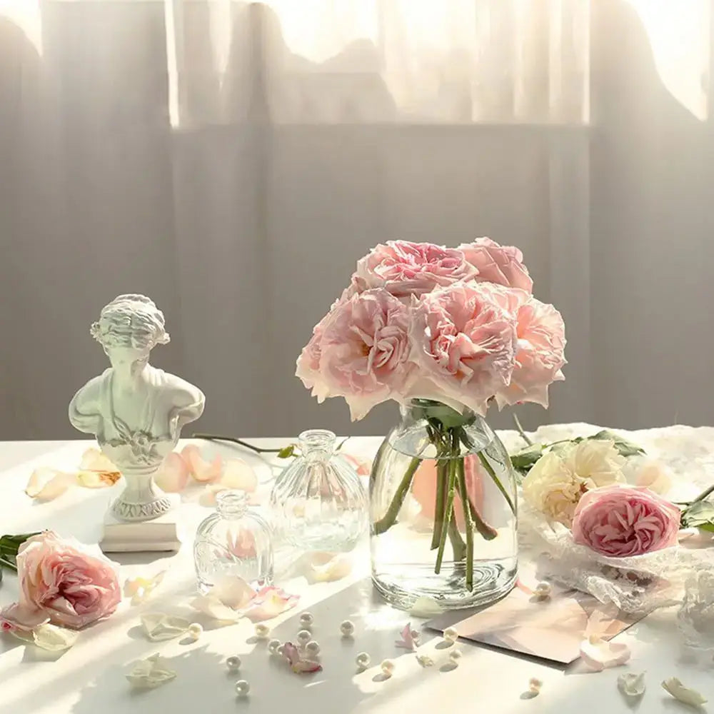 A clear glass vintage relief vase holding soft pink roses designed for hydroponic plants by decorbites