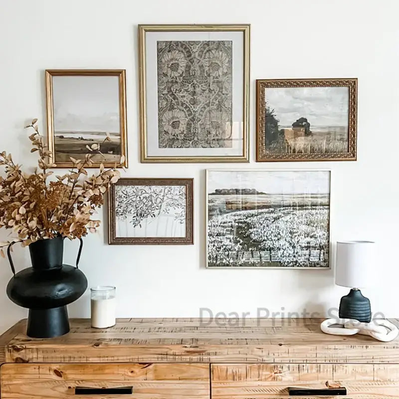 Set of five framed black and white prints with ornate gold frames above wooden console featuring summer landscape vintage style