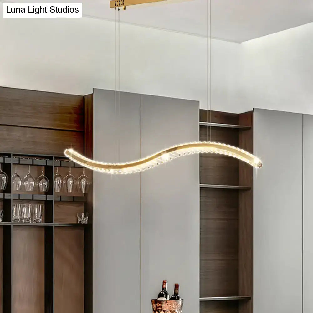 A gold decorbites wavy k9 crystal led pendant light with embedded crystals for dining room ceiling use