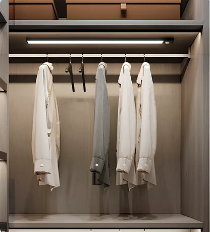 Decorbites™ wireless under cabinet lighting illuminating a sleek minimalist closet with white and gray dress shirts