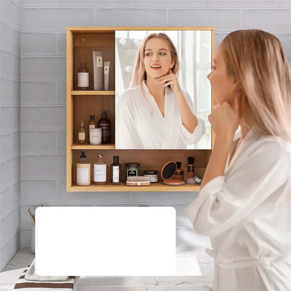 Decorbites™ wood medicine cabinet with light wood frame mirror and three shelves holding toiletries with woman reflection