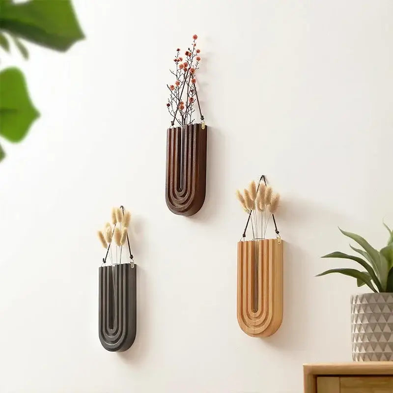 Three modern wooden flower vase wall mount holders in brown gray and natural wood with vertical grooves and hanging cords