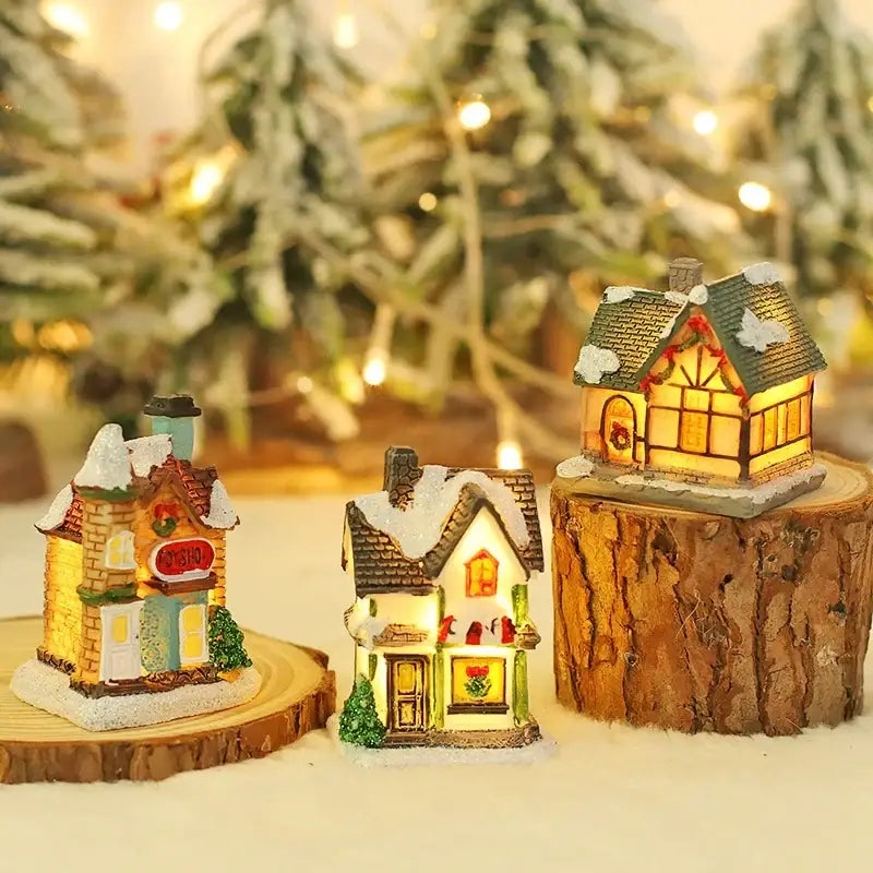 Three miniature decorbites wooden led light house christmas decorations with snow dusted roofs and glowing windows