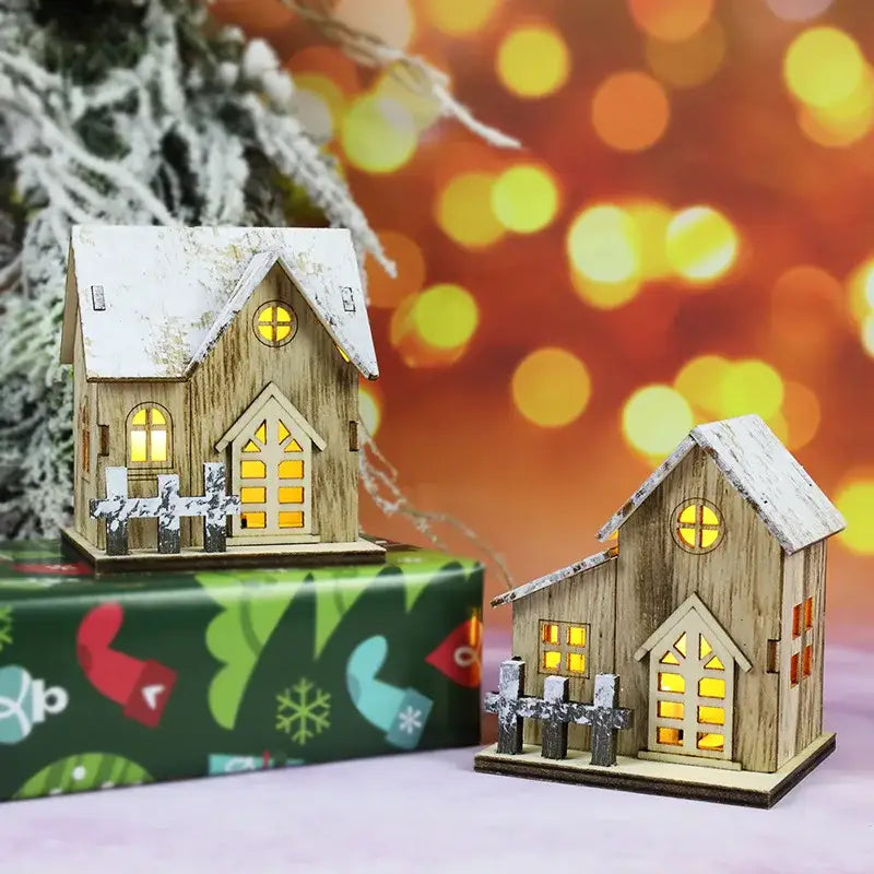 Two miniature wooden led light houses with snow-dusted roofs and glowing yellow windows for christmas decor
