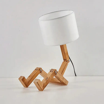 Minimalist wooden robot shape table lamp with white cylindrical shade and articulated legs for indoor study lighting