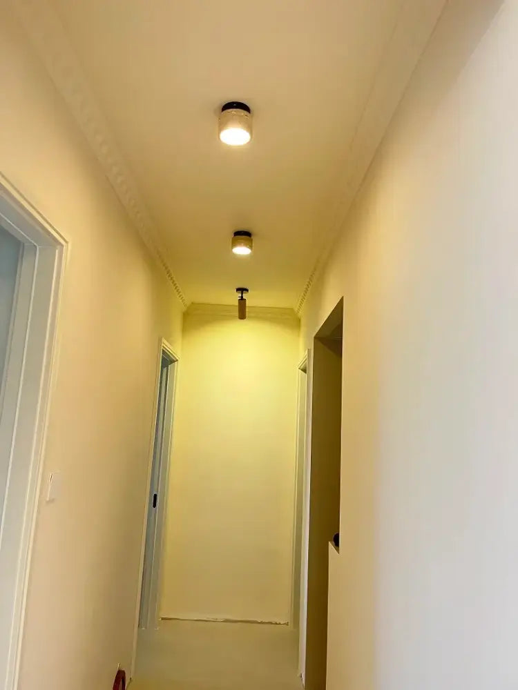 Two cylindrical recessed ceiling lights with black fixtures and warm white illumination in DecorBites yellow marble ceiling light design