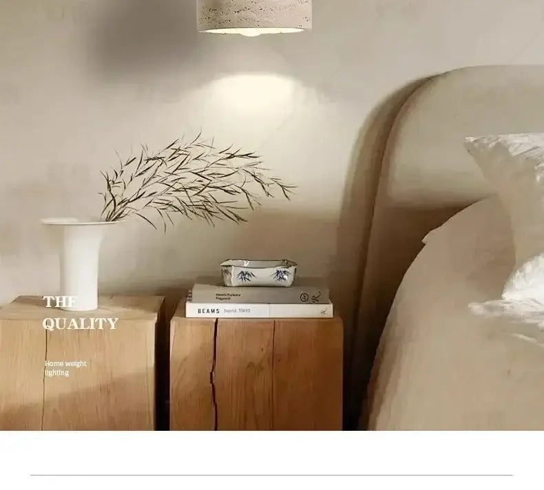 White ceramic vase with slender neck and flared rim holding dried branches near yellow stone led pendant chandelier