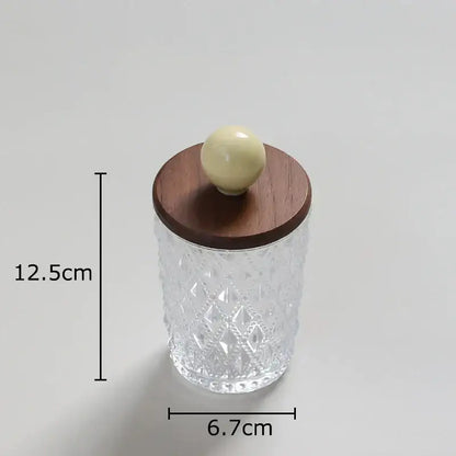 Clear glass jewelry jar with diamond pattern and walnut lid topped by off-white colorful ceramic ball knob