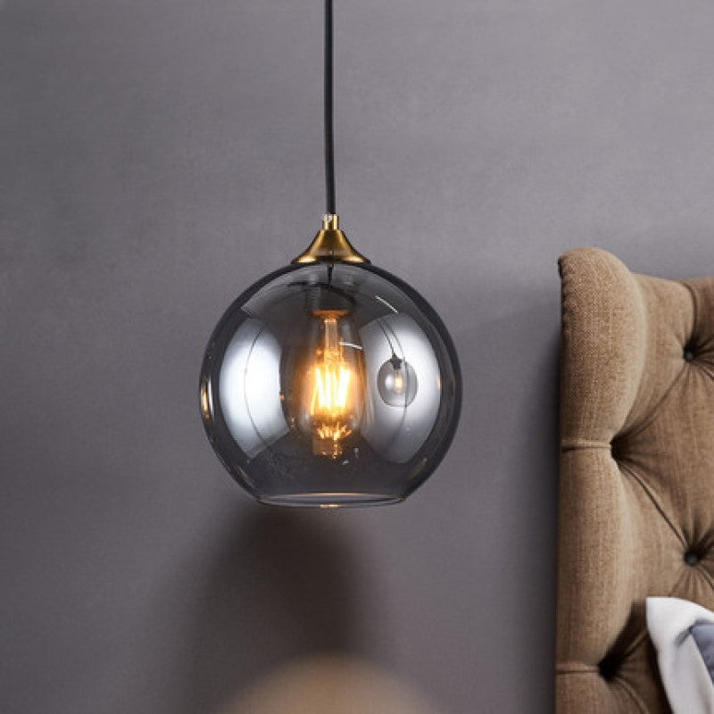 Glass globe pendant light with brass accents and modern design suitable for dining room chandelier and bedside use