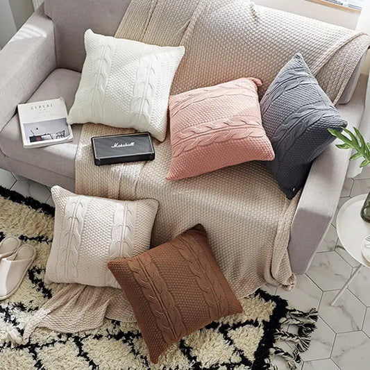 Set of five double cable knit cushion covers in cream, blush pink, slate gray, beige, and brown for living room use