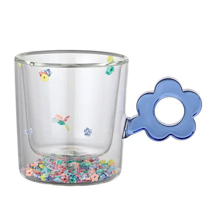 Clear double wall glass mug with blue flower handle and embedded glitter flowers filled with colorful beads for kitchen use
