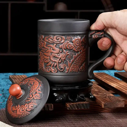 Black ceramic dragon phoenix thermo coffee mug with intricate reddish-brown dragon relief and matching lid orange knob
