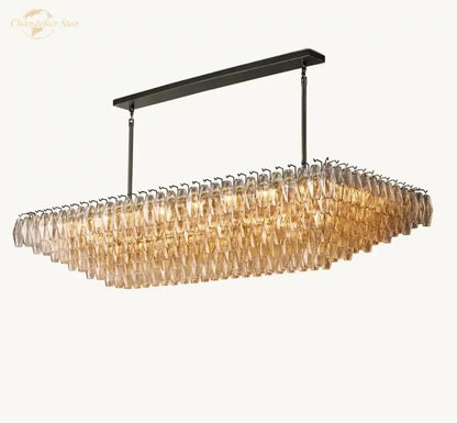 A modern rectangular dining room pendant light with a black metal frame and amber tinted clear glass tiered crystals