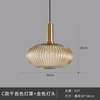 A modern glass pendant light with a ribbed translucent amber shade and polished gold metal fixture for dining room