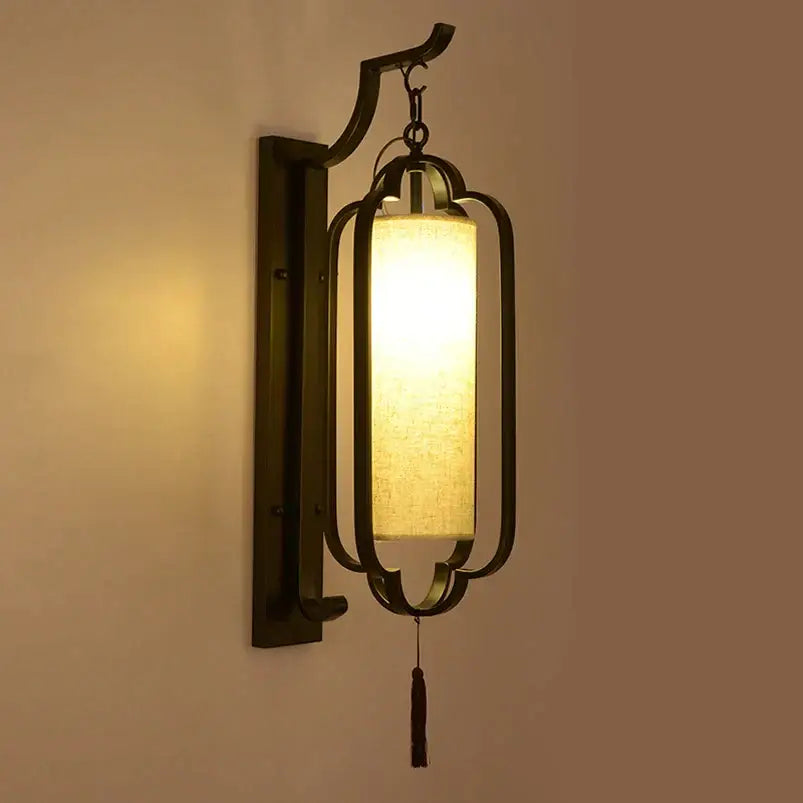 Elegant black wrought iron wall sconce lamp with a warm rectangular fabric shade and a dangling tassel for bedroom lighting