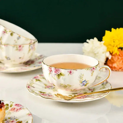 Elegant blue and pink floral porcelain tea cup set featuring a delicate white cup with gold rim and handle for dining room use