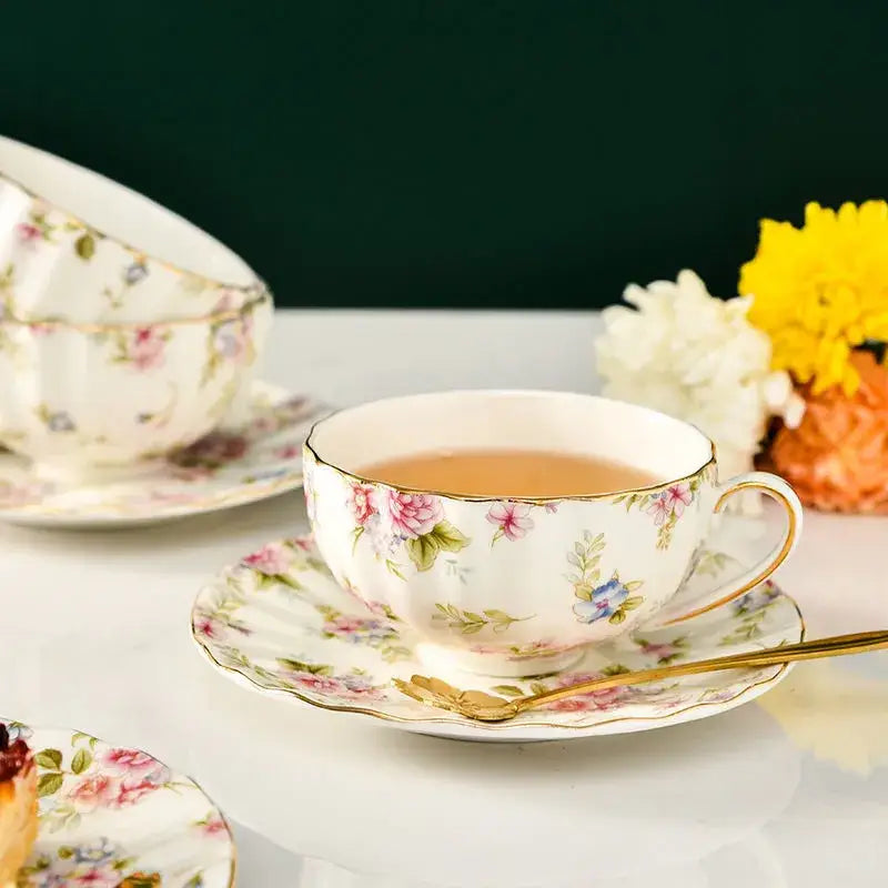 Elegant blue and pink floral porcelain tea cup set featuring a delicate white cup with gold rim and handle for dining room use