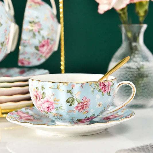 Elegant blue and pink floral porcelain tea cup set featuring a light blue cup with rose pattern and gold trim on a saucer