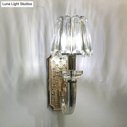 Elegant brass and crystal tapered cone sconce light with clear crystal shade and ornate diamond pattern mounting plate