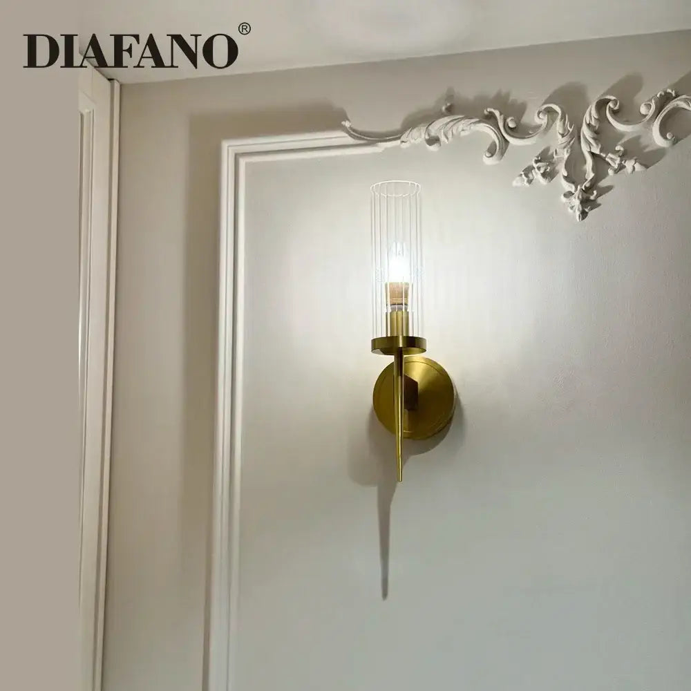 Elegant brass and black glass tube wall sconce with gold-toned copper wall sconce featuring clear glass cylinder vertical ridges