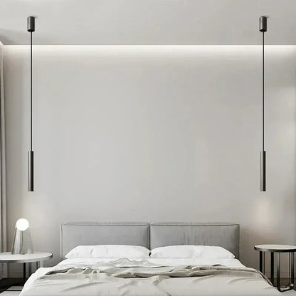 Two sleek matte black cylindrical decorbites elegant brass pendant lights hang symmetrically above a bed