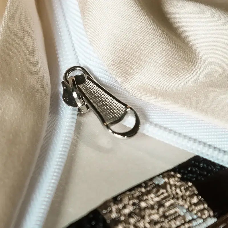 Silver-toned metal zipper pull with textured grid surface on elegant brown and cream 200s embroidery egyptian cotton bedding set