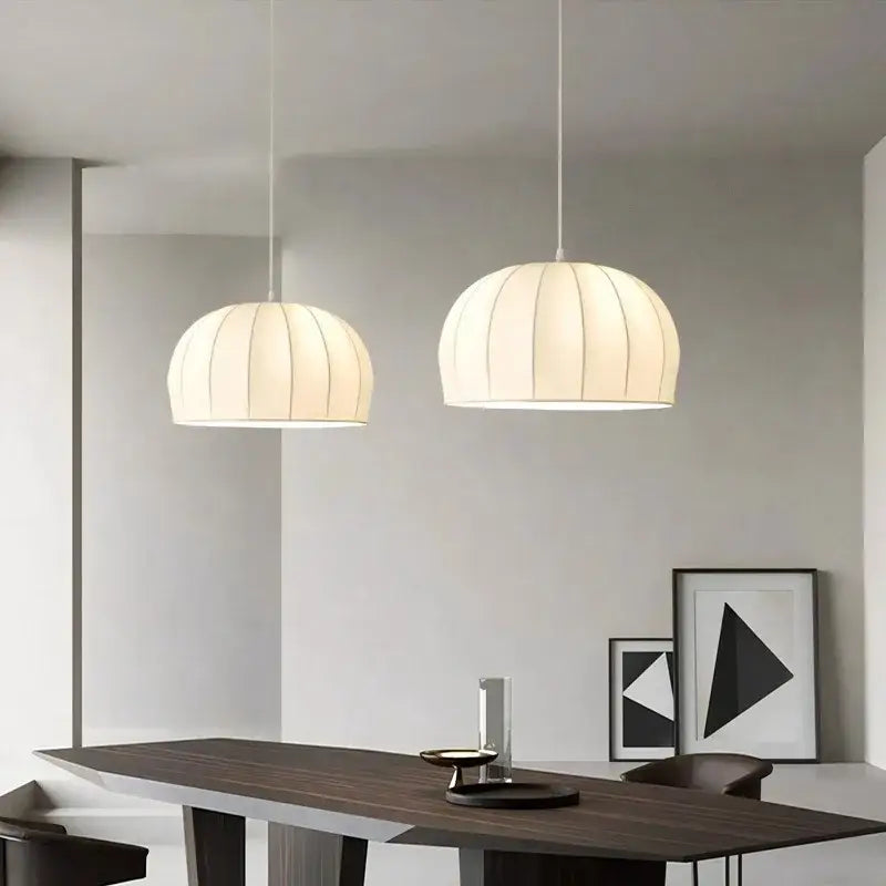 Two off-white cream ribbed silk pendant lights hang over a dark wood table decorbites elegant silk pendant light for dining room