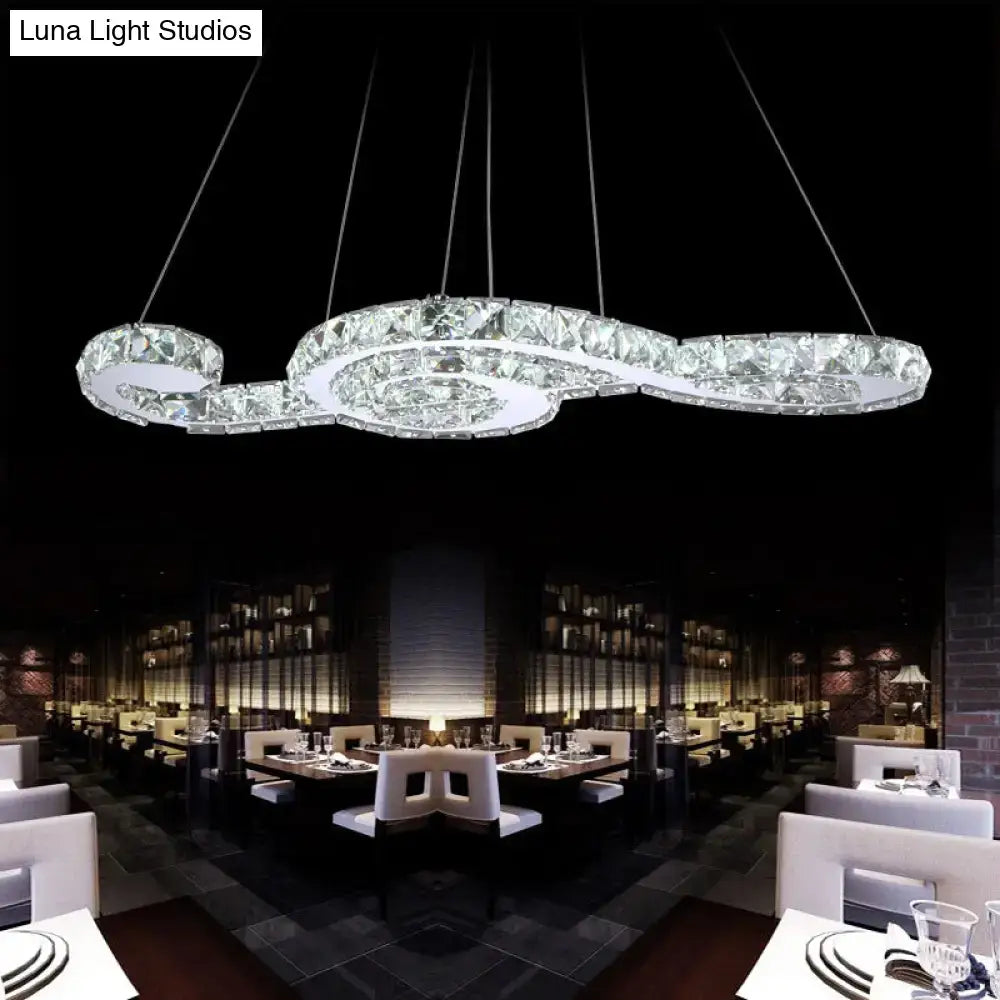 A crystal-encrusted musical note pendant light with sleek curved design and white warm third lighting for fashion stores