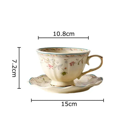 Cream-colored elegant floral ceramic cup and saucer set with pink and green patterns and gold-trimmed porcelain rim and handle
