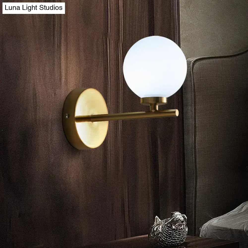 Elegant brass-finished wall sconce with frosted ivory glass globe, perfect wall light for bedroom decor