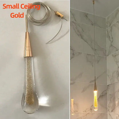 A small gold-toned decorbites crystal glass led pendant light with clear teardrop filled with golden glitter for dining room decor