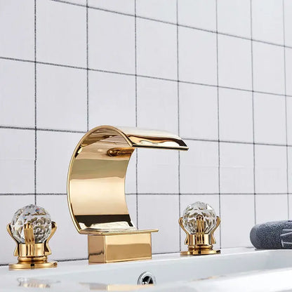Elegant gold-toned basin faucet set with crystal knob handles and waterfall spout for bathroom use