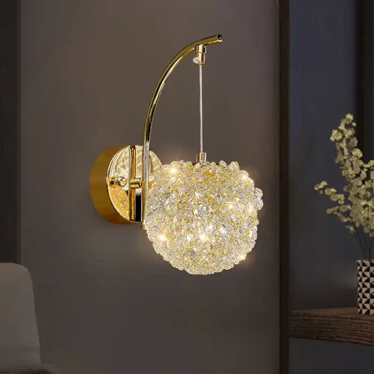 Elegant gold crystal wall lamp with curved arm and warm glowing spherical globe for bedroom sconce lighting decorbites crystal wall