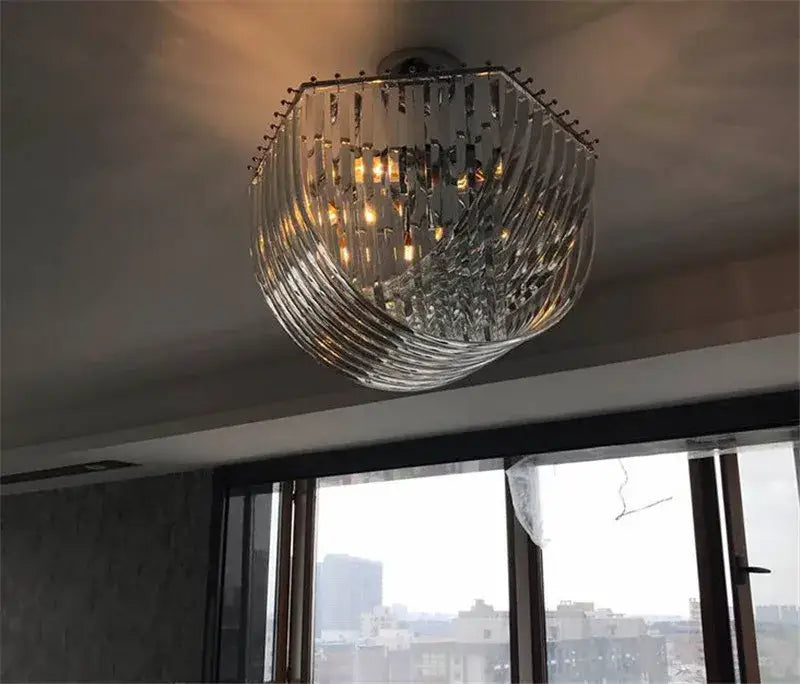 Elegant gold glass tube pendant chandelier with clear glass prisms swirling around an illuminated central frame