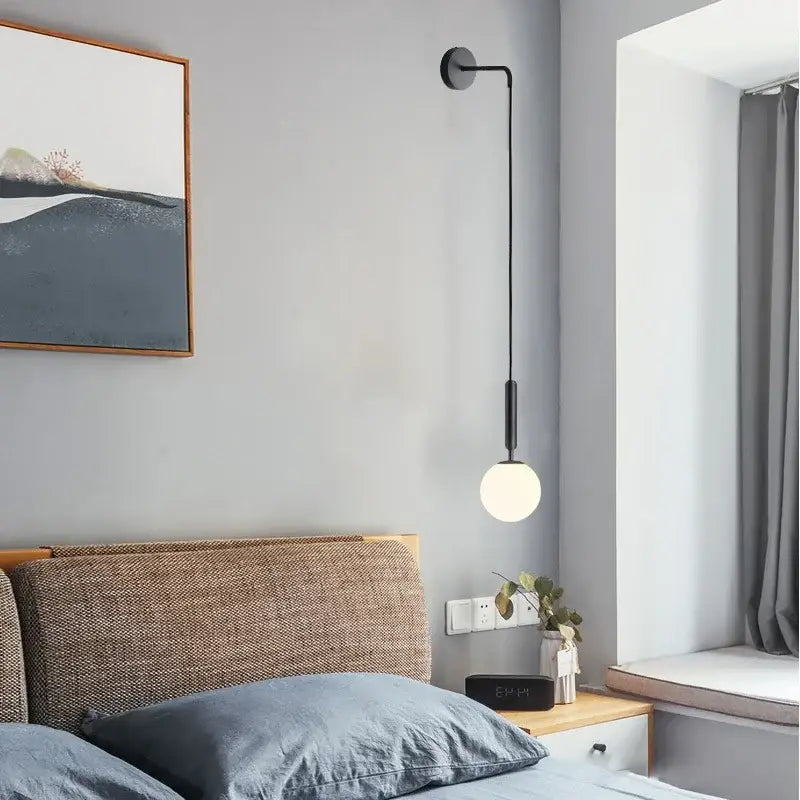 Black minimalist wall lamp with sleek curved arm and frosted glass globe by decorbites elegant glass for living room decor