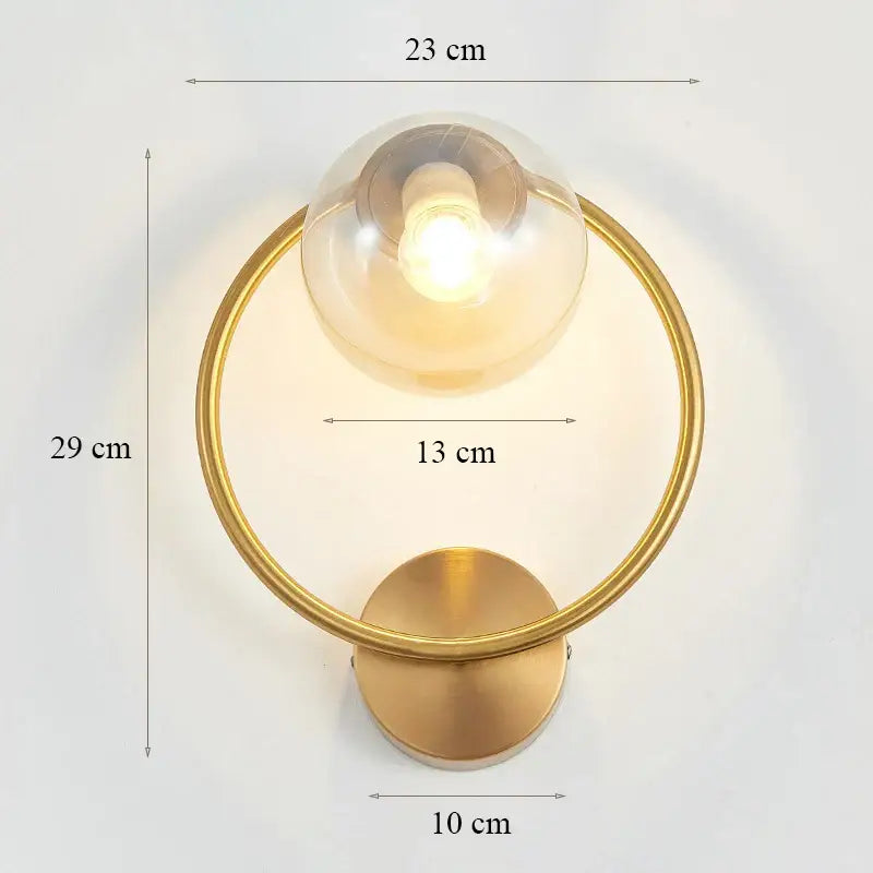 Elegant gold iron wall lamp with circular frame and clear glass globe designed as a modern decorbites iron wall lamp