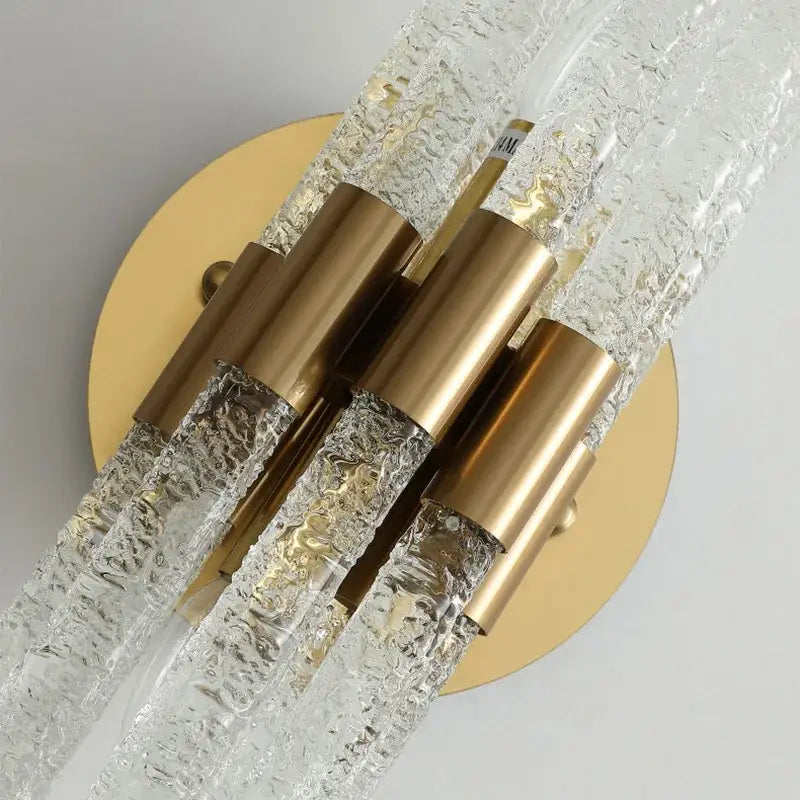Elegant gold metal wall sconce with clear textured glass rods and gold-toned caps for modern bedroom decorbites gold metal