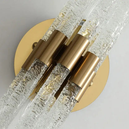 Elegant gold metal wall sconce with clear textured glass rods and gold-toned caps for modern bedroom decorbites gold metal