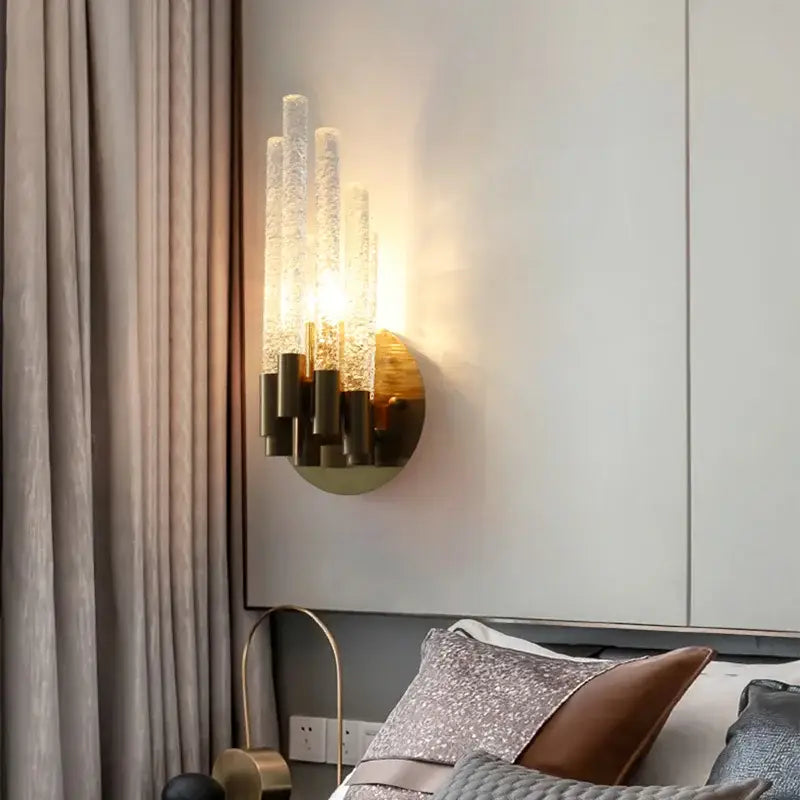 Elegant gold metal wall sconce with five textured translucent glass tubes emitting warm light for bedroom decorbites gold metal