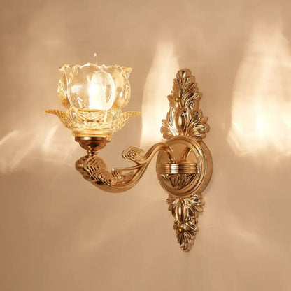 Elegant gold scrolled arm wall mount sconce featuring an ornate design and crystal glass tulip-shaped shade for bedrooms