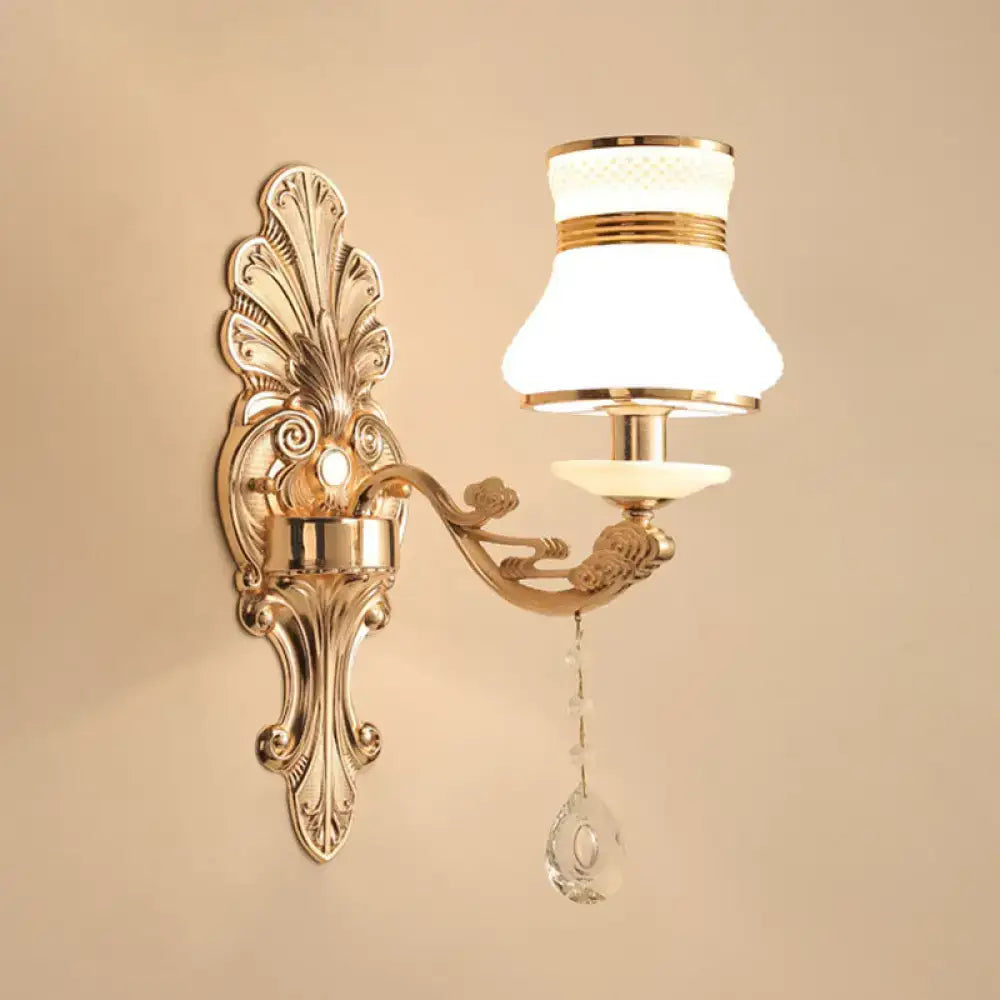 Elegant gold scrolled arm wall mount sconce with frosted glass shade and dangling crystal droplet for bedroom lighting
