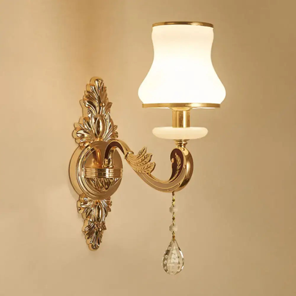Elegant gold scrolled arm wall mount sconce with white frosted glass shade and crystal teardrop pendant for bedroom lighting