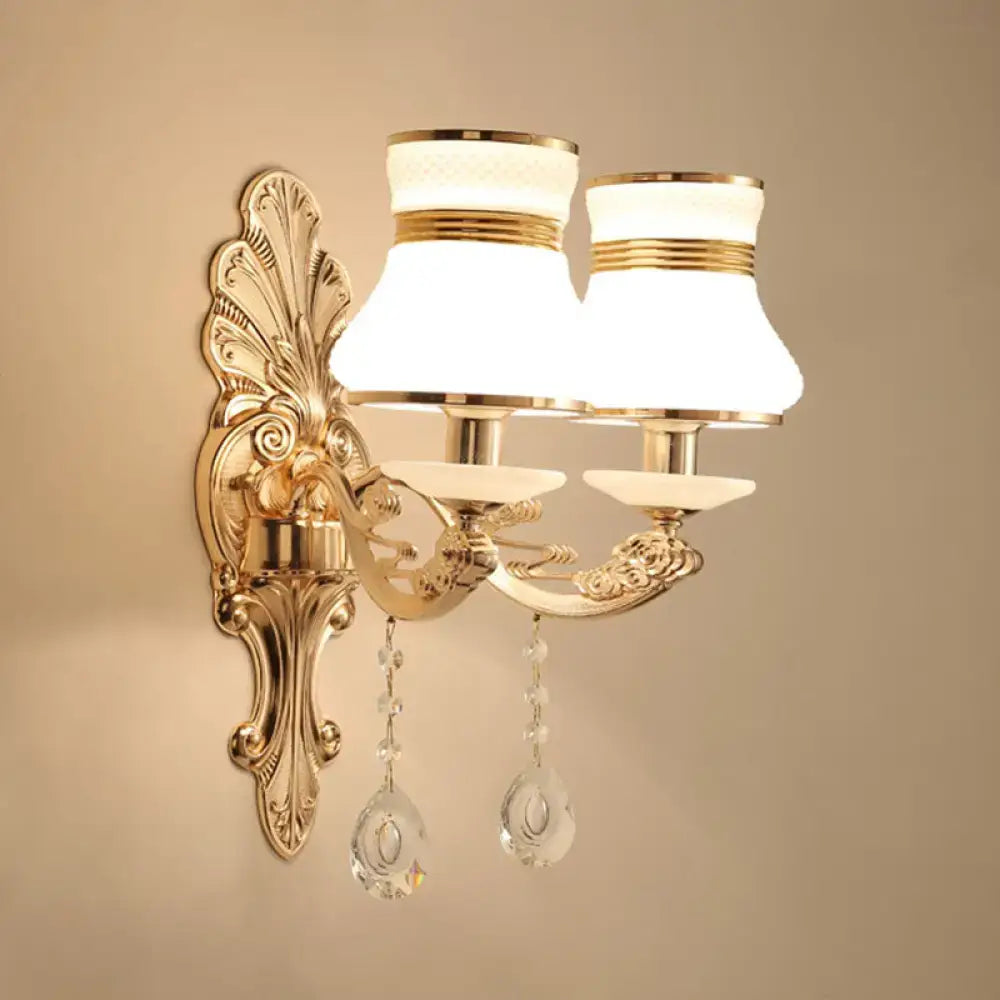 Elegant gold scrolled arm wall mount sconce with frosted glass shades and crystal teardrop pendants for bedrooms