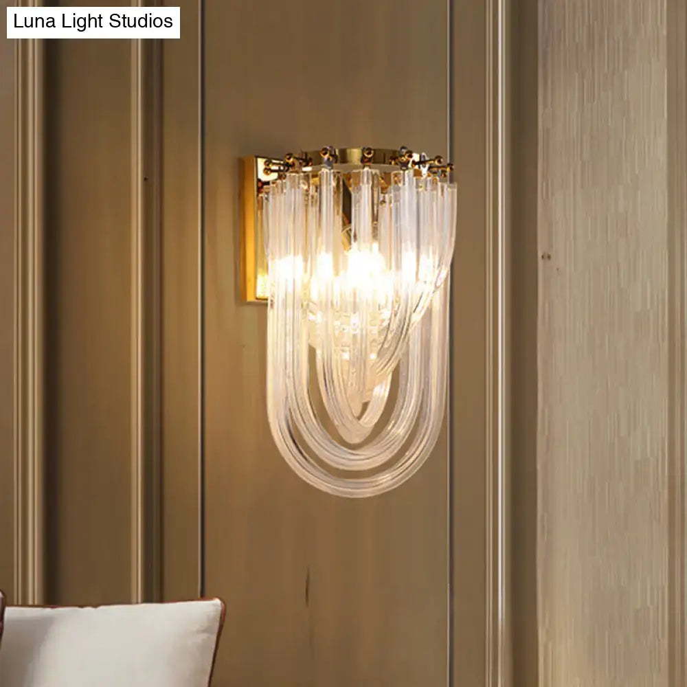 Elegant gold wall lamp with a twisted crystal shade featuring a gold frame and cascading clear glass tubes for bedroom use