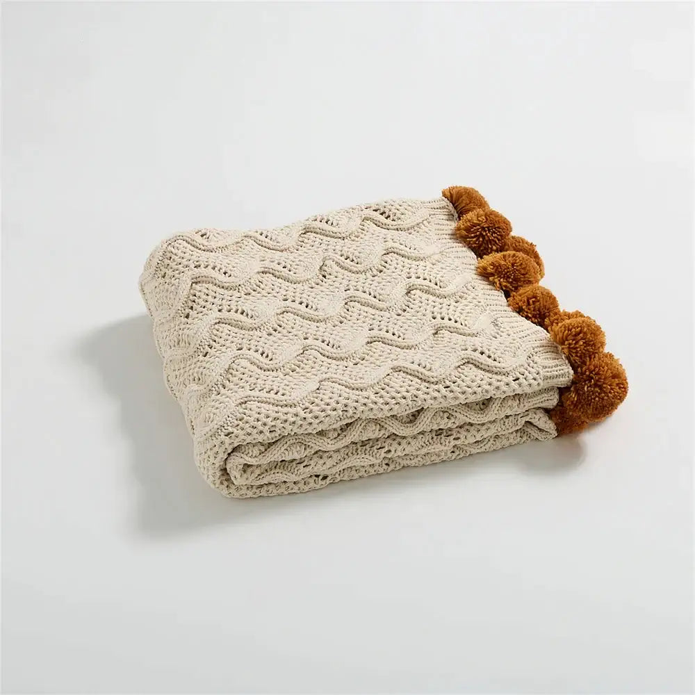 Beige knitted throw blanket with wavy cable pattern and brown pom-pom trim for decorbites elegant chenille decor