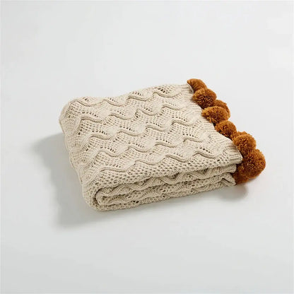 Beige knitted throw blanket with wavy cable pattern and brown pom-pom trim for decorbites elegant chenille decor