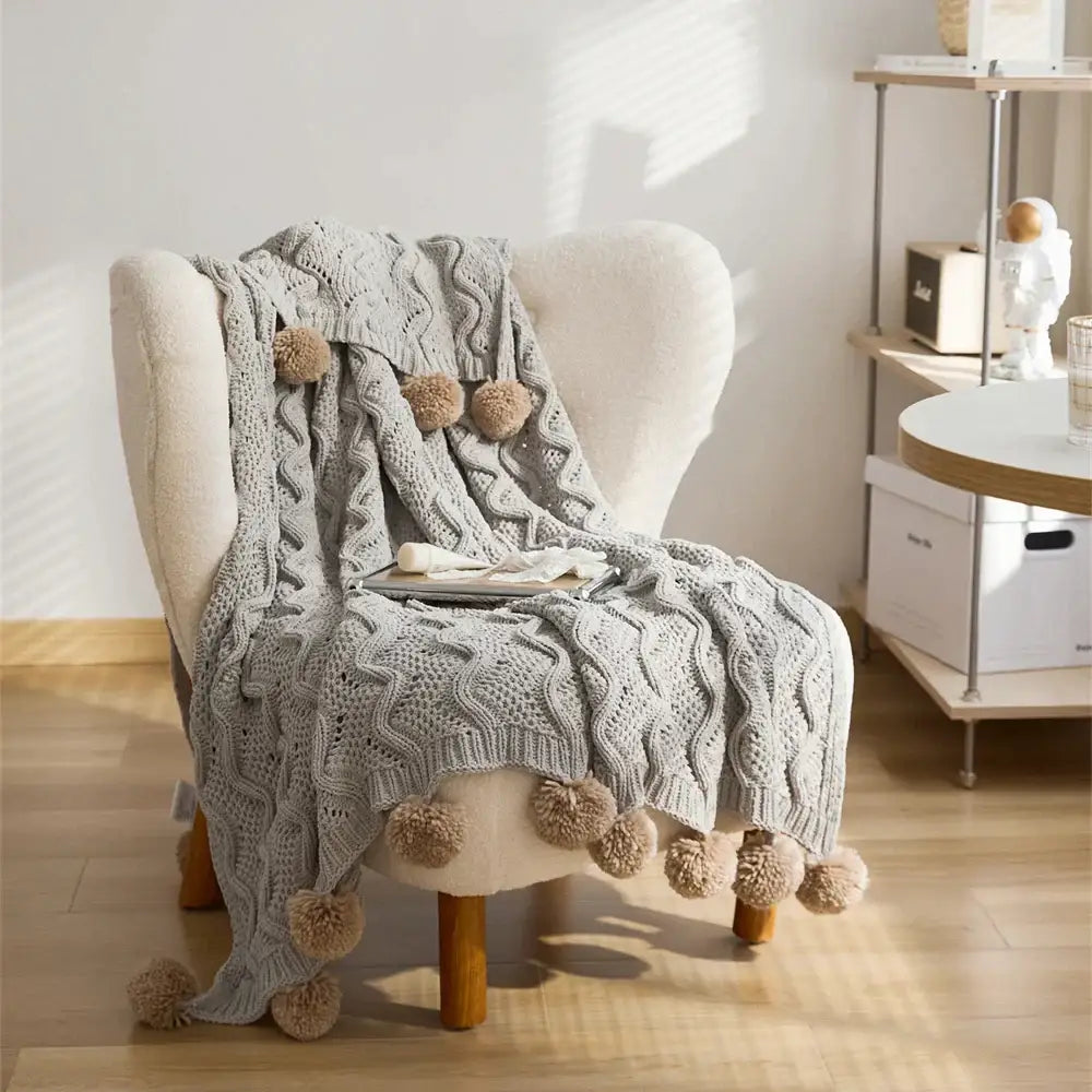 Elegant gray chenille throw blanket with textured cable patterns and beige pompons for light gray decorbites decor