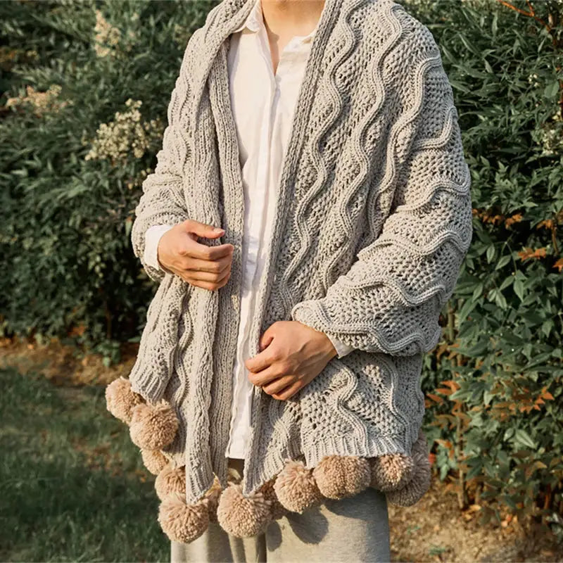 A cozy light gray cable knit cardigan with beige elegant chenille pompons complements decorbites elegant chenille throw blanket
