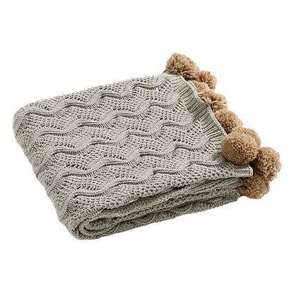 A soft light gray chenille throw blanket with wavy cable pattern and elegant chenille pompons for beige decorbites decor